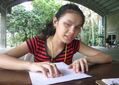 Girl reading braille at outdoor camp