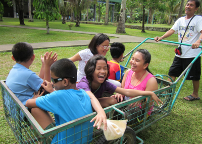 Group of blind children riding in a cart at outdoor camp